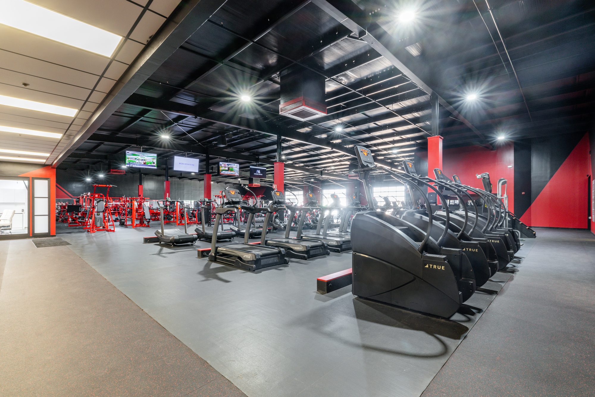 TB Fitness Club fitness floor with cardio equipment and dramatic starburst ceiling lighting
